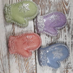 May include: Four ceramic mitten-shaped dish soap holders. The holders are decorated with a snowflake design and have a pearl-like finish. The colors are green, purple, pink, and blue.