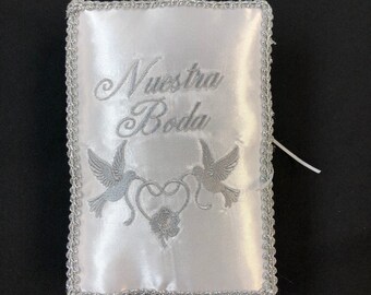 May include: White satin pillow with silver embroidered trim and the words "Nuestra Boda" and two doves with a heart in the center.