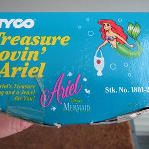 May include: A blue box with a picture of Ariel from Disney's The Little Mermaid. The box says "TYCO Treasure Lovin' Ariel" and "Stk. No. 1801-2".