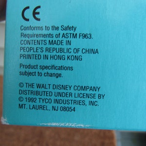 May include: A blue box with white text that reads "CE Conforms to the Safety Requirements of ASTM F963. CONTENTS MADE IN PEOPLE'S REPUBLIC OF CHINA PRINTED IN HONG KONG Product specifications subject to change. &copy; THE WALT DISNEY COMPANY DISTRIBUTED UNDER LICENSE BY &copy; 1992 TYCO INDUSTRIES, INC. MT. LAUREL, NJ 08054"
