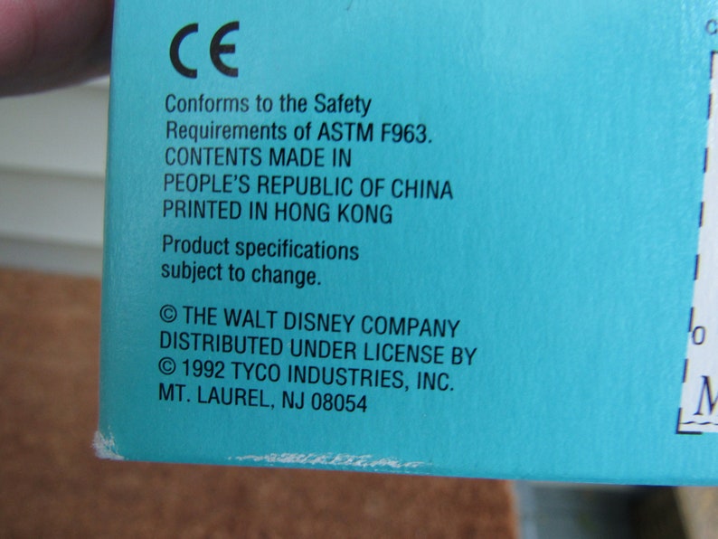 May include: A blue box with white text that reads "CE Conforms to the Safety Requirements of ASTM F963. CONTENTS MADE IN PEOPLE'S REPUBLIC OF CHINA PRINTED IN HONG KONG Product specifications subject to change. &copy; THE WALT DISNEY COMPANY DISTRIBUTED UNDER LICENSE BY &copy; 1992 TYCO INDUSTRIES, INC. MT. LAUREL, NJ 08054"