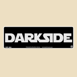 May include: Black and white rectangular sticker with the word "DARKSIDE" in white letters on a black background. The sticker has copyright information and the text "Produced by StarShine Arts Inc. www.starshinearts.com".