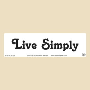 以下が含まれることがあります： 「Live Simply」という黒い文字が書かれた白い長方形のステッカー。ステッカーには、「© 2019 JR723」という著作権情報、「Produced by Starshine Arts Inc.」というテキスト、および「www.starshinearts.com」というウェブサイトも記載されています。