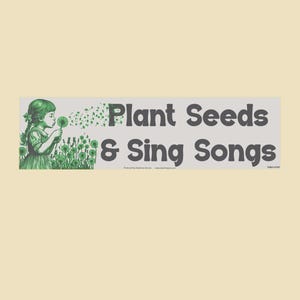May include: A rectangular sticker with the text "Plant Seeds & Sing Songs" in dark gray. A green illustration of a girl blowing dandelion seeds is on the left. The background is a light beige color.