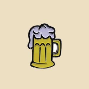 May include: A yellow and black enamel pin of a beer stein with a purple foam top.