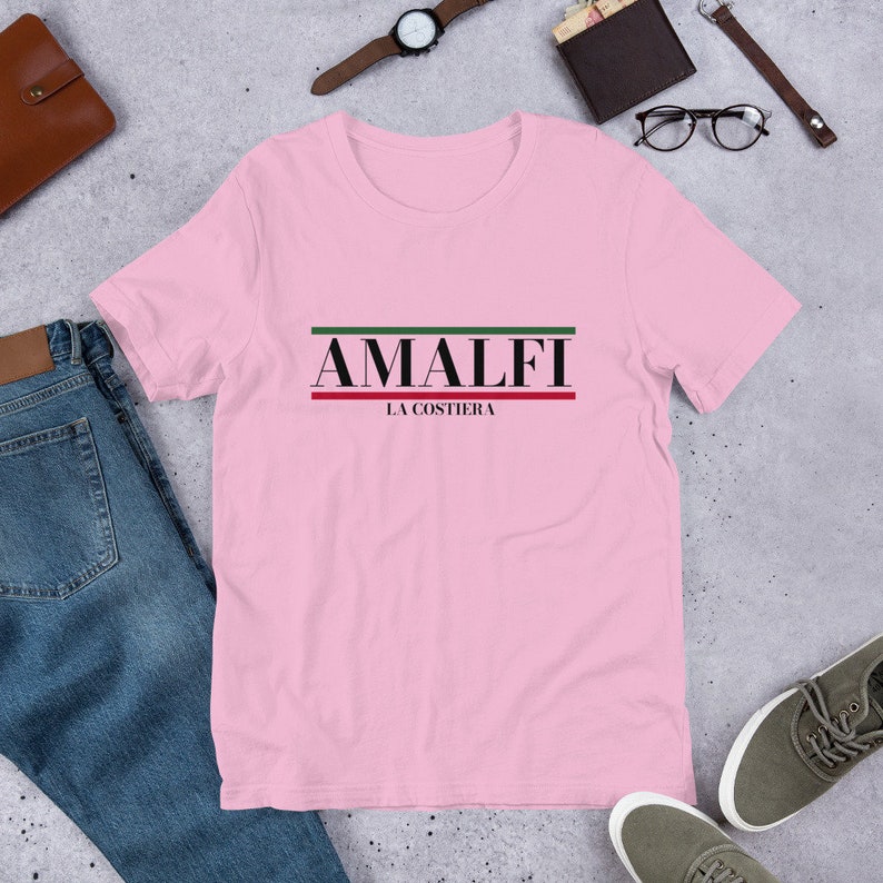 K&ouml;nnte beinhalten: Rosa T-Shirt mit schwarzem Text "AMALFI LA COSTIERA" mit gr&uuml;nen und roten Streifen &uuml;ber und unter dem Text.
