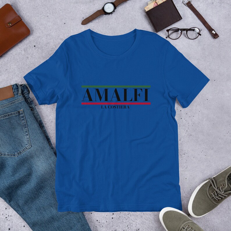 K&ouml;nnte beinhalten: Ein k&ouml;nigsblaues T-Shirt mit einem schwarzen Grafikdruck, auf dem "Amalfi La Costiera" mit gr&uuml;nen und roten Streifen steht.