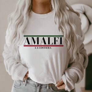 K&ouml;nnte beinhalten: Wei&szlig;es Langarmshirt mit schwarzem Text "Amalfi La Costiera" mit gr&uuml;nen und roten Streifen &uuml;ber und unter dem Text.