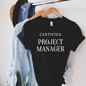 May include: Black t-shirt with white text that reads "CERTIFIED PROJECT MANAGER".