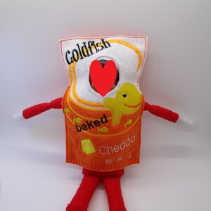 May include: A felt elf costume shaped like a box of Goldfish crackers. The box is orange and white with the words "Goldfish", "baked", and "Cheddar" on it. There is a small yellow fish illustration on the box.