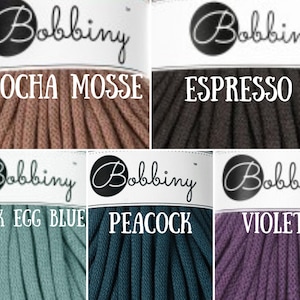 Puede incluir: Seis carretes de cuerda de algod&oacute;n en diferentes colores. Los colores son moca, espresso, azul huevo de pato, pavo real y violeta. Cada carrete tiene una etiqueta blanca con la palabra "Bobbiny" en negro y el nombre del color en negro.