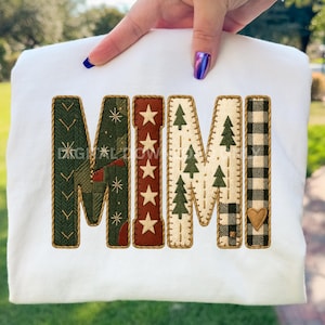 Könnte beinhalten: Weißes Sweatshirt mit dem Wort "MIMI" in einem Patchwork-Design. Die Buchstaben weisen verschiedene Muster auf, darunter grüne Fischgrätenmuster, rote Sterne und grüne Weihnachtsbäume. Der Buchstabe "I" hat einen herzförmigen Aufnäher.
