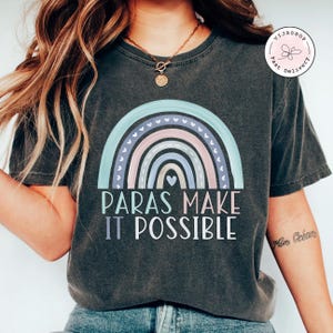 May include: A dark gray t-shirt with a rainbow design and the text "Paras Make It Possible".