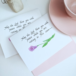 May include: A white card with a purple flower illustration and the text "May the Lord bless you with peace while you are resting in His care."