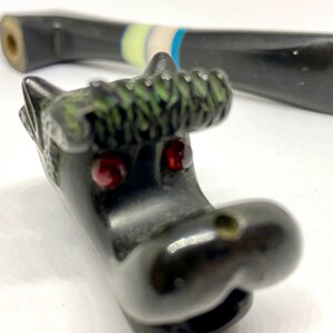 May include: Black decorative bottle stopper featuring a hippo head with red gem eyes and green accents. The stopper has a detailed design and a smooth, glossy finish. Another black stopper is in the background.