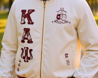 Puede incluir: Chaqueta bomber color crema con detalles burdeos y cremallera dorada. Presenta letras griegas burdeos "KAΨ" y un escudo. La chaqueta tiene "Est. 1911" impreso. La chaqueta tiene ribete a rayas burdeos y blanco.