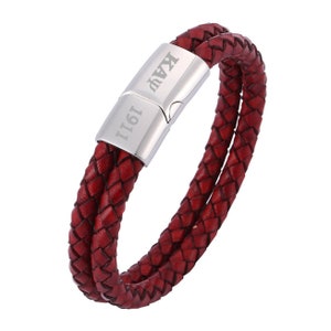 May include: A red leather bracelet with a silver clasp engraved with "1911 Kay".