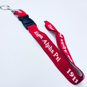 May include: Red lanyard with white text that reads "Kappa Alpha Psi 1911".