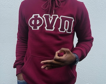 Puede incluir: Una sudadera con capucha color granate con un logotipo bordado en blanco "ΦΥΠ" en la parte delantera. La sudadera tiene una capucha con cordón y un bolsillo canguro.