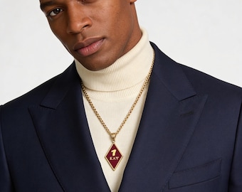 Pode incluir: Um colar de corrente em tom dourado com um pingente em forma de diamante com incrustação de esmalte vermelho escuro. O pingente exibe o numeral 1 dourado acima das letras gregas Kappa Alpha Psi, como KAY, centralizado na moldura.