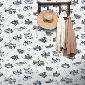 May include: White wallpaper with a repeating pattern of ducks swimming in a pond. A wooden coat rack with a straw hat and two jackets hanging on it.