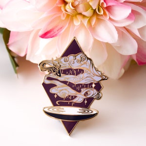 Pu&ograve; includere: Uno spillo in smalto dorato con uno sfondo a forma di diamante viola. Lo spillo presenta un design bianco e oro di nuvole vorticose e gocce di pioggia sopra un piatto circolare bianco e nero.