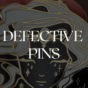 May include: A black and gold enamel pin featuring a stylized face with long, flowing white hair. The pin has a detailed design with star accents and the words "DEFECTIVE PINS" in white lettering.