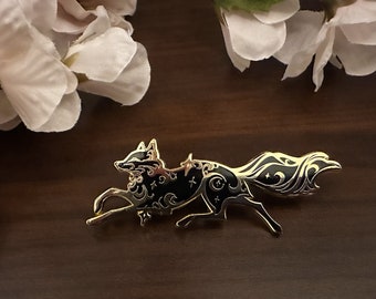 May include: A gold-toned metal pin featuring a black silhouette of a stylized fox running with a swirling tail. The fox is decorated with white stars and crescent moons.