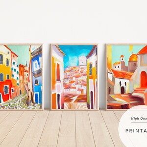 May include: Three colourful paintings depicting a street scene in a European city. The paintings feature bright colours, including yellow, orange, red, blue, and green. The buildings are painted in a stylised manner, with rounded corners and whimsical details. The paintings are framed in wood and are ready to hang.