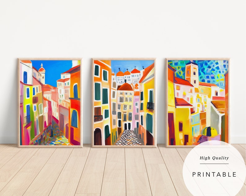 May include: Three colourful paintings of a narrow street in a European city. The buildings are painted in shades of yellow, orange, red, and blue. The street is cobbled and there are trees and plants on either side.