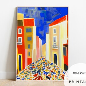 May include: A colourful abstract painting depicting a cobbled street in a European city. The buildings are painted in shades of red, yellow and blue, and the sky is a bright blue. The cobblestones are a mix of colours, including red, yellow, blue, green and white.