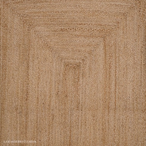 Puede incluir: Una alfombra de fibra natural con un patr&oacute;n tejido. La alfombra es de color marr&oacute;n claro y tiene una forma rectangular.