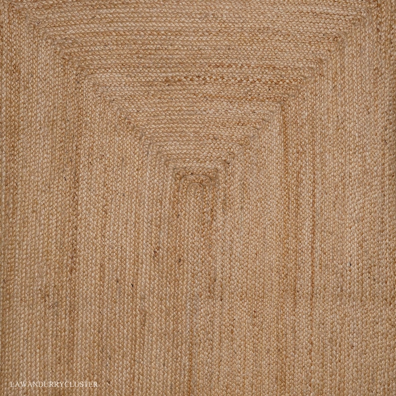 Puede incluir: Una alfombra de fibra natural con un patr&oacute;n tejido. La alfombra es de color marr&oacute;n claro y tiene una forma rectangular.