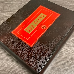 May include: A dark brown wooden box with a red and gold label that says "Sun Grown".