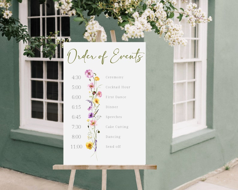 May include: A white sign with the words "Order of Events" written in green script. The sign lists the order of events for a wedding reception with times and descriptions, such as "Ceremony", "Cocktail Hour", "First Dance", "Dinner", "Speeches", "Cake Cutting", "Dancing", and "Send off". A floral illustration with pink, purple, yellow, and white flowers decorates the left side of the sign.