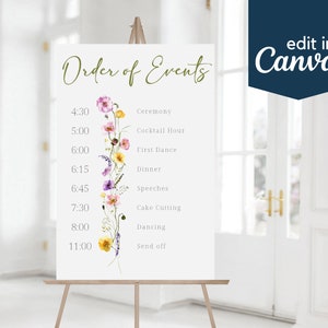May include: A white sign with the words "Order of Events" in green script. The sign lists the order of events for a wedding reception, including the time and event name. The sign is decorated with a watercolor floral design.