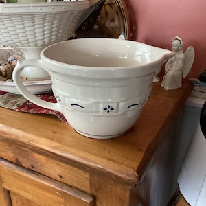 May include: A white ceramic mixing bowl with a blue and white floral design. The bowl has a handle and a spout.