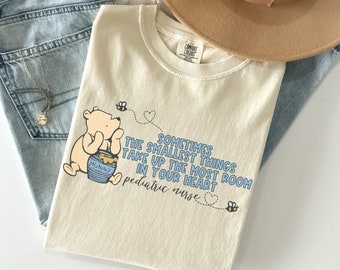 May include: A cream colored t-shirt with a Winnie the Pooh illustration and the text "Sometimes the smallest things take up the most room in your heart. Pediatric nurse."