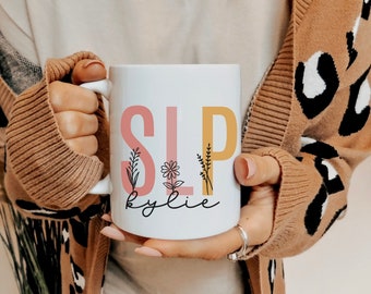 Könnte beinhalten: Weiße Keramiktasse mit einem rosa und gelben Design, auf dem "SLP" mit einem floralen Design und dem Namen "kylie" darunter steht.