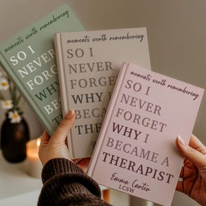 May include: Three hardcover journals in sage green, beige, and light pink. Each cover features the text "moments worth remembering" and "SO I NEVER FORGET WHY I BECAME A THERAPIST". The pink journal includes the name "Emma Carter LCSW" at the bottom.