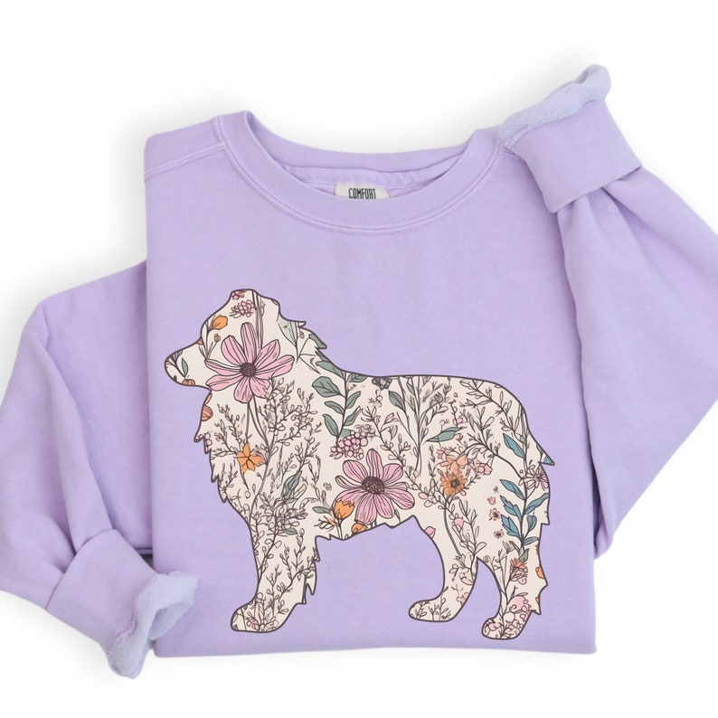 Pu&ograve; includere: Una felpa color lavanda con una stampa floreale a forma di silhouette di Australian Shepherd.