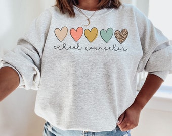 May include: Gray sweatshirt with a row of five colorful hearts and the text "school counselor" printed on the front.