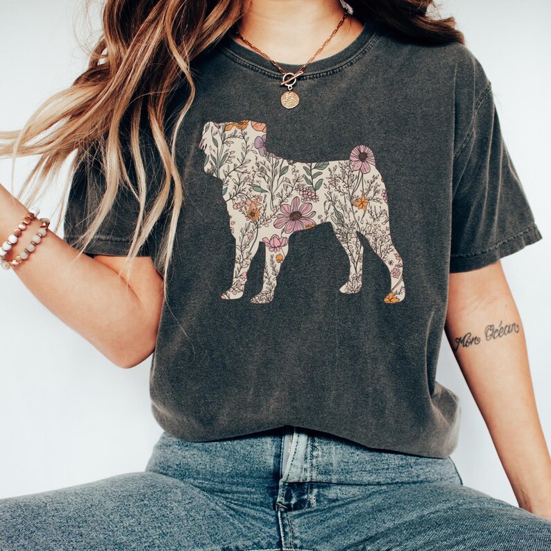 May include: A dark gray t-shirt with a floral print of a Shar-Pei dog silhouette. The shirt has a crew neck and short sleeves.