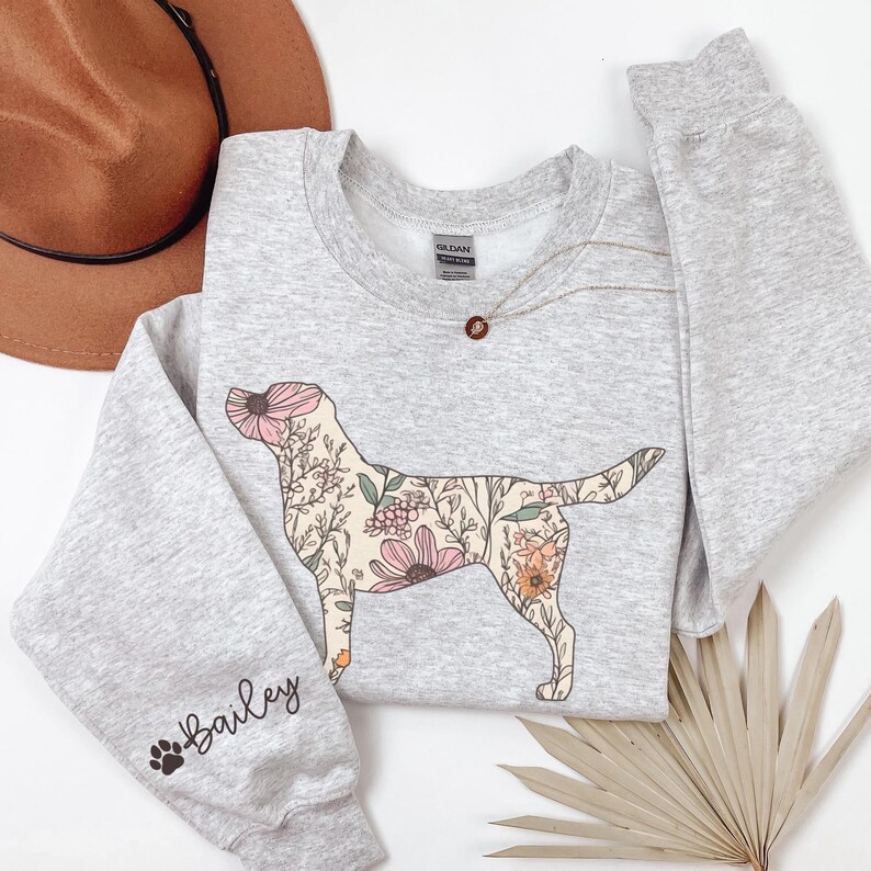 May include: A gray sweatshirt with a floral dog silhouette on the front and the name "Bailey" with a paw print on the left sleeve.