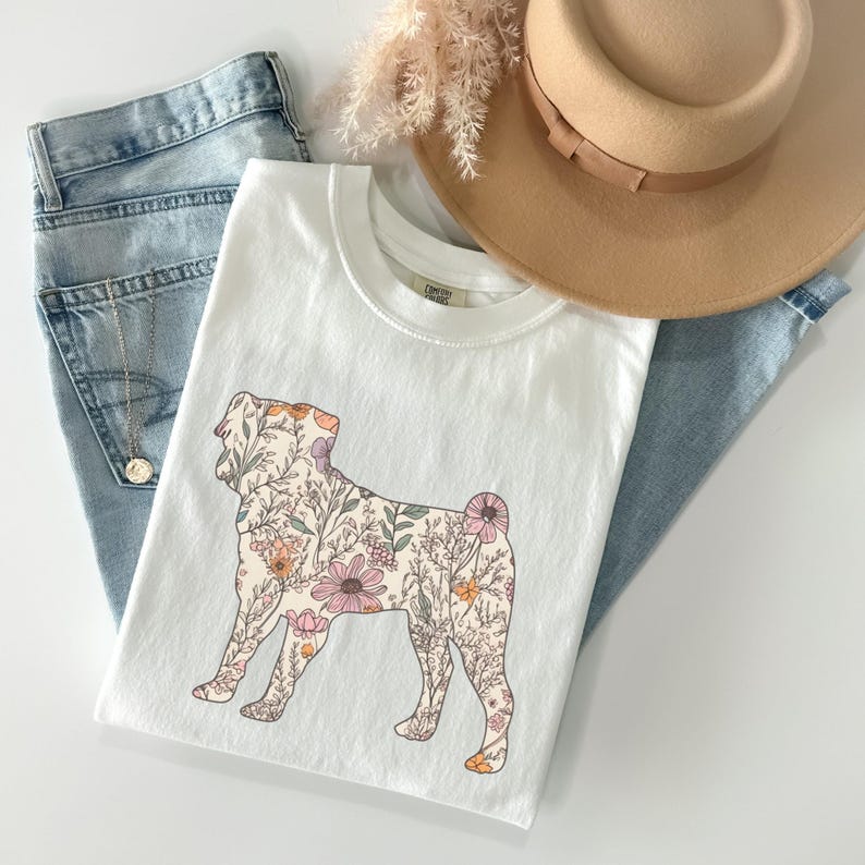 May include: White t-shirt with a floral design in the shape of a dog. The flowers are pink, orange, and yellow.