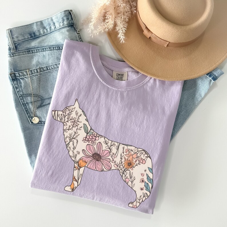 May include: A lavender t-shirt with a floral design in the shape of a wolf silhouette. The shirt has the text "Comfort Colors" on the tag.