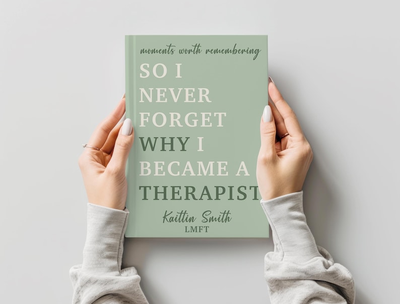 May include: A sage green book with white and dark green text that reads: moments worth remembering SO I NEVER FORGET WHY I BECAME A THERAPIST, followed by the author name Kaitlin Smith and the professional designation LMFT in a serif font.