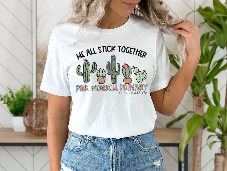 May include: White t-shirt with a graphic of cacti and the text "We all stick together Pine Meadow Primary Ms. Miller"