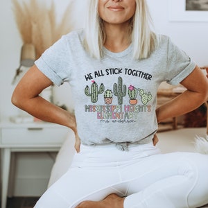 May include: A grey t-shirt with a cactus graphic and the text "We all stick together Mississippi Heights Elementary Mrs. Anderson".