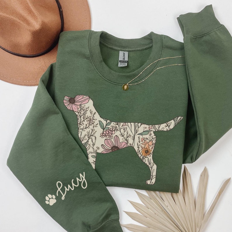 May include: A green sweatshirt with a floral dog silhouette on the front and the word "Lucy" on the left sleeve.